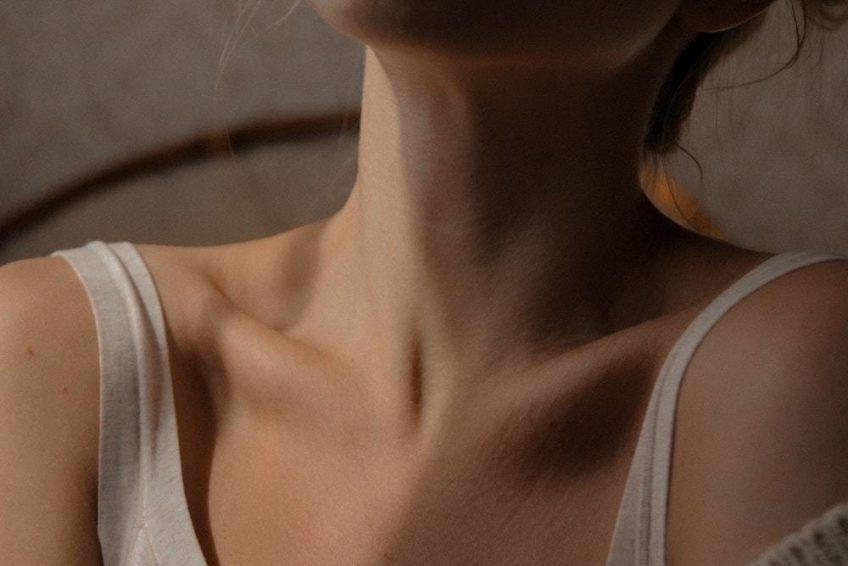 Close-up of hands on a woman's neck.
