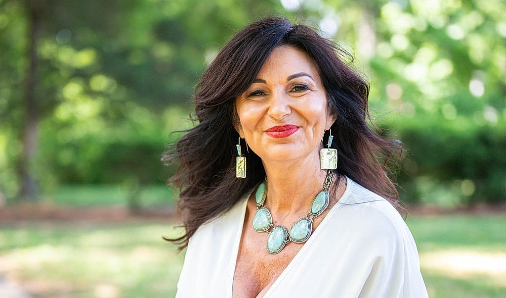 Smiling woman wearing elegant jewelry outdoors.