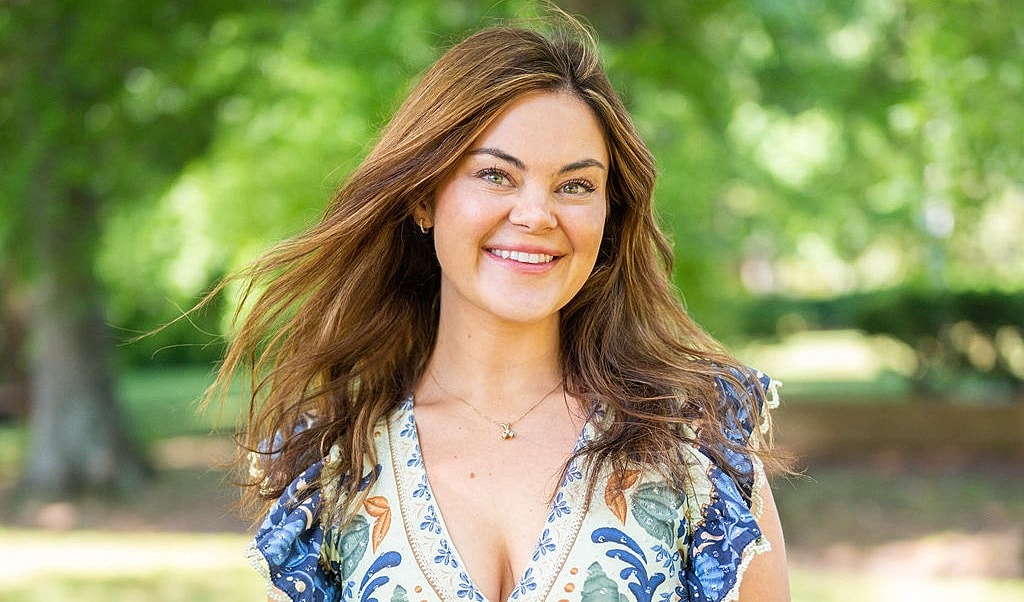 Smiling woman in a colorful dress outdoors.
