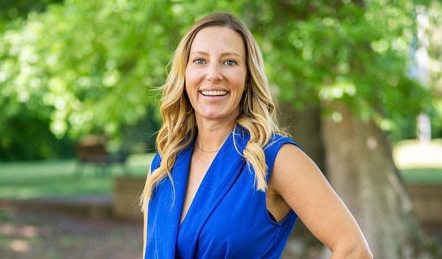 Smiling woman in a blue dress outdoors.