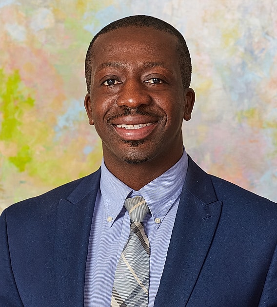 Smiling man in a suit against colorful background.