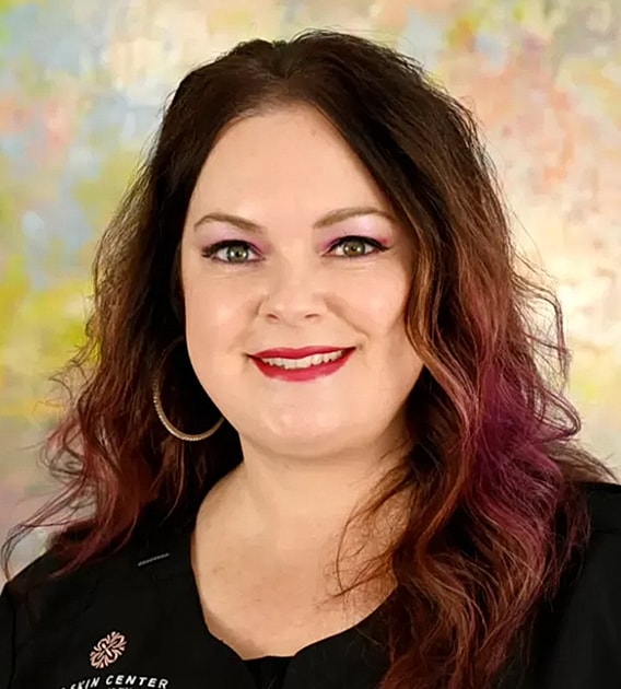 Smiling woman with colorful hair and makeup.