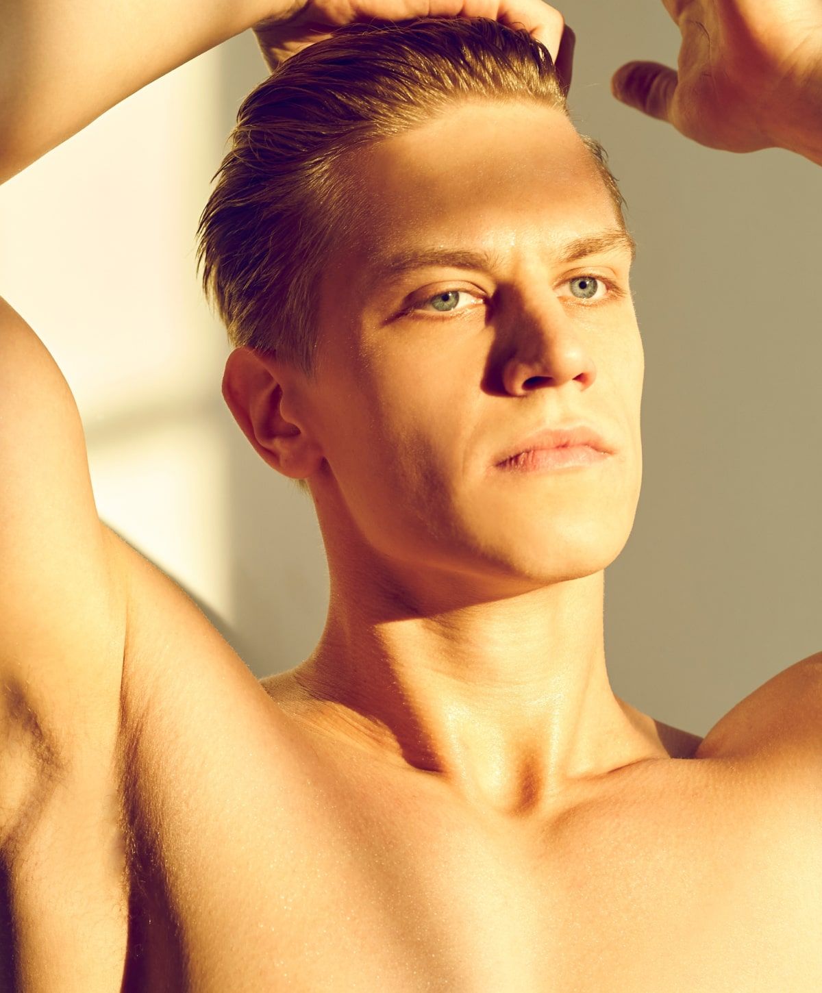 Young man with slicked-back hair in sunlight.