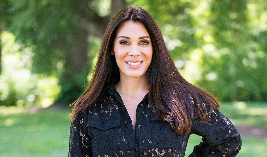 Smiling woman in a park wearing a black top.