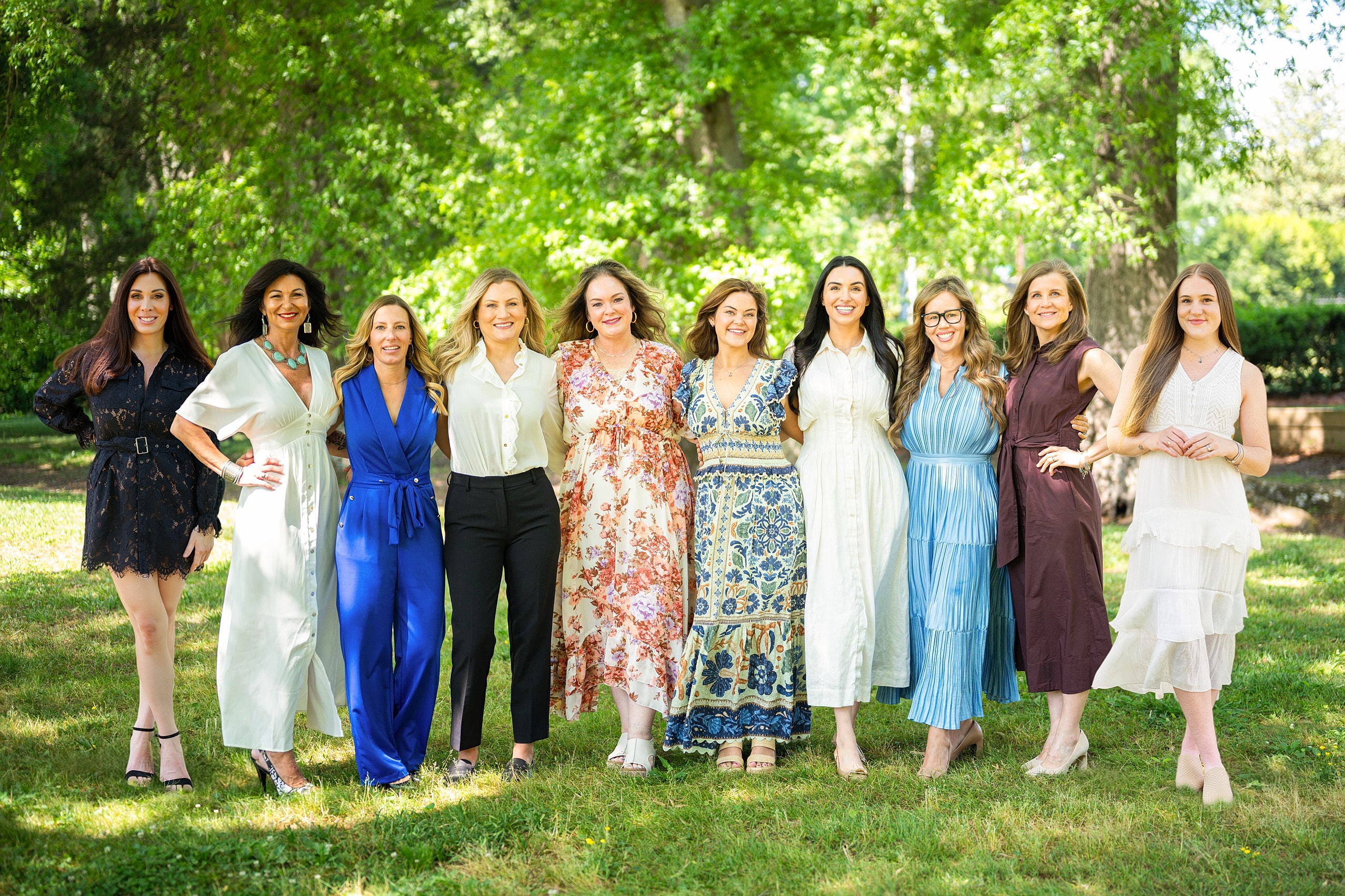 Group of medical aesthetic providers posing outdoors in vibrant dresses.