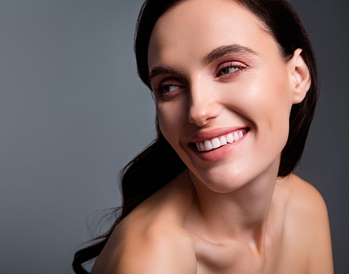 Smiling woman with natural makeup and soft lighting.