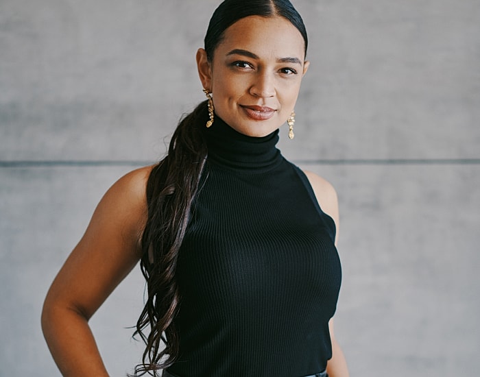 Smiling woman in black turtleneck and earrings.